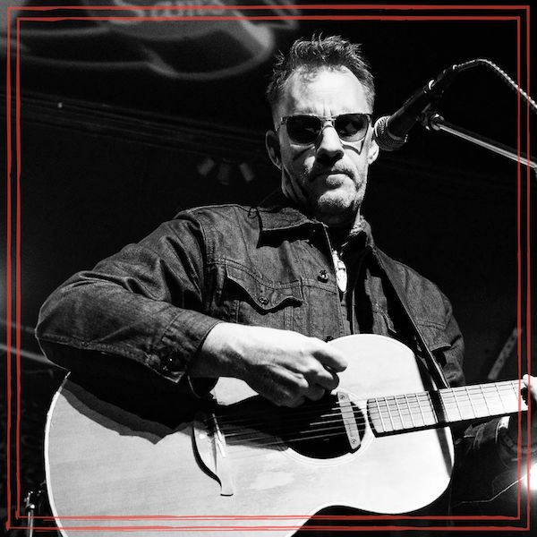 Episode art featuring black & white photo of Chris Taylor, on stage with acoustic guitar, wearing sun glasses. (Image by JoJoDancerPhotos)