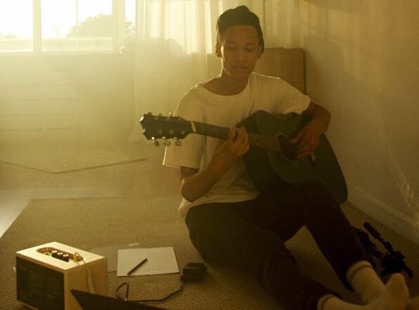 Young man sitting on floor playing guitar | Image by @artempodrez on Pexels.com | https://www.pexels.com/photo/a-young-man-sitting-on-the-floor-playing-guitar-4680179/